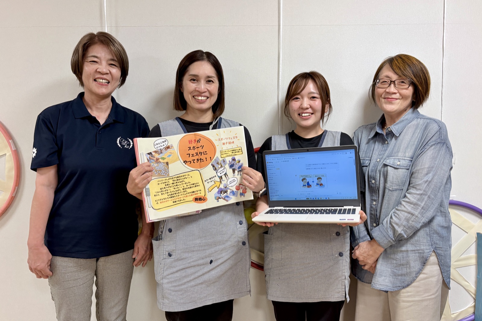 ヒナリーで作った掲示物とパソコンを手に並ぶ、認定こども園リアンかしい保育園の園長と先生方
