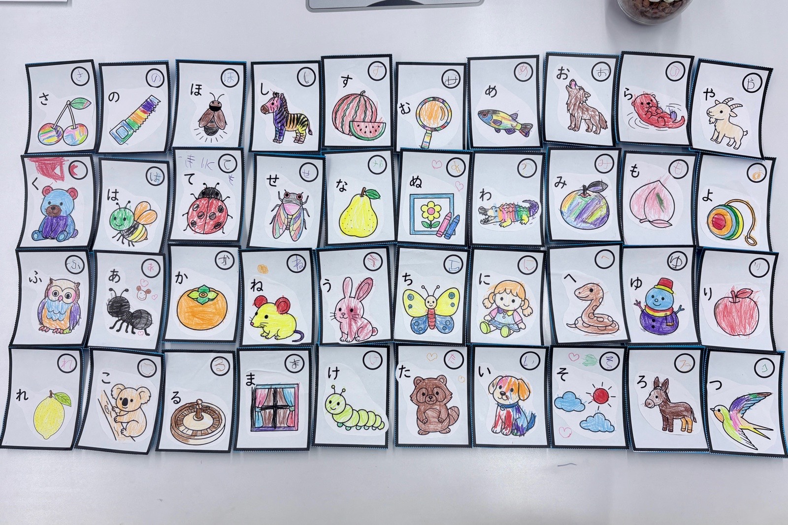 ヒナリーが作った塗り絵をもとに、子どもたちが文字を書き色を塗って仕上げた50音のカルタ